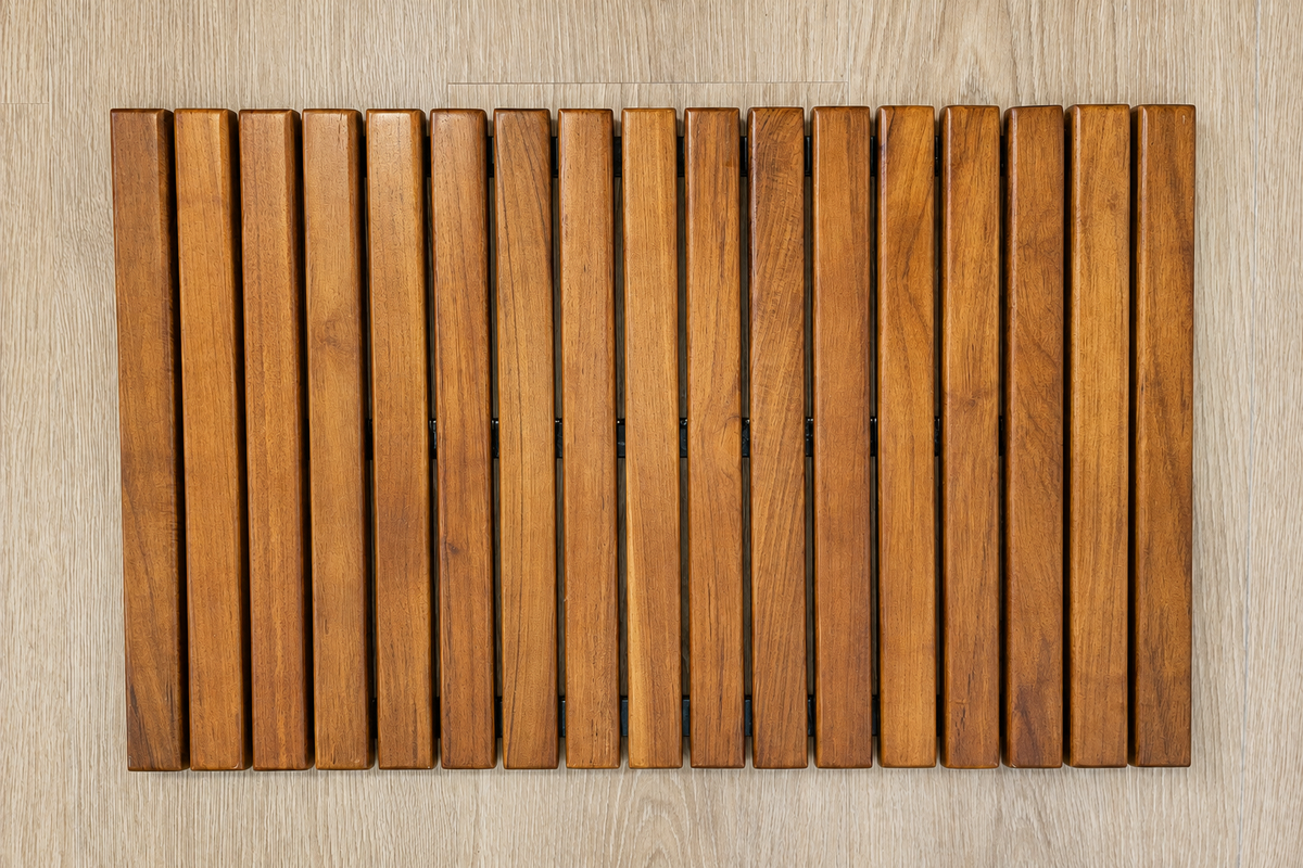 Roll-up teak shower mat laid flat with richer natural teak color